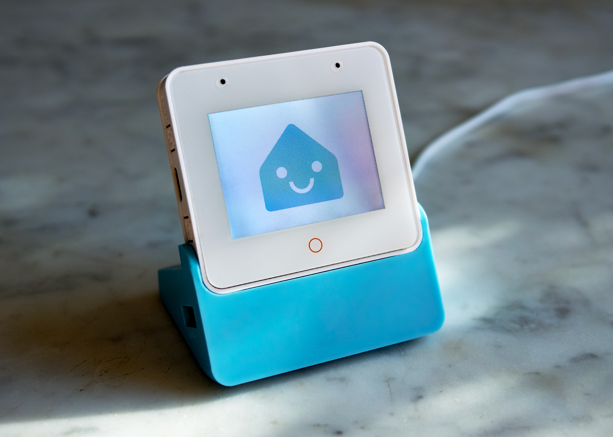 An ESP32-S3-Box-3 running the Home Assistant voice assistant, displaying the Home Assistant mascot, on a marble countertop